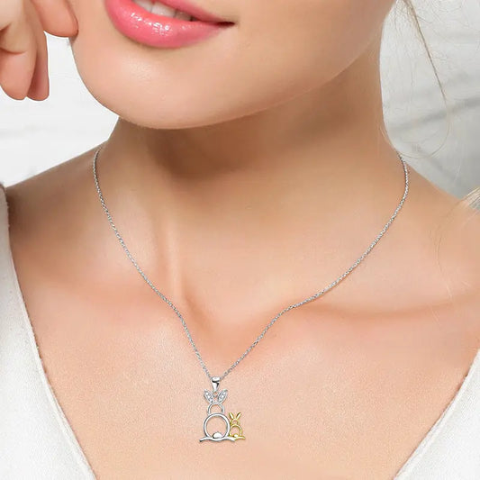 Close-up of a woman wearing a delicate silver necklace featuring a bunny pendant with gold accents against a neutral background.
