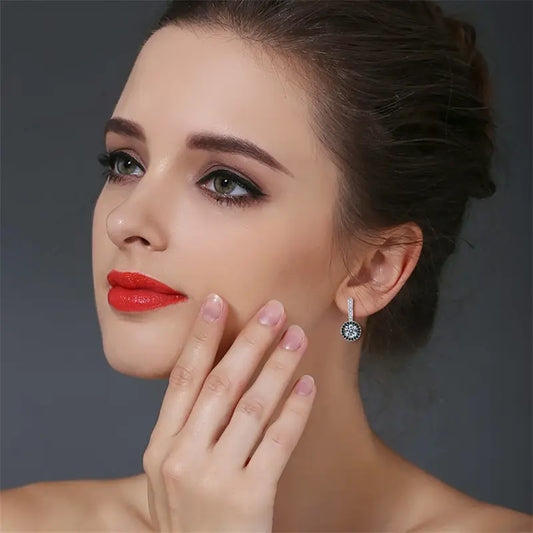 A person with a hand on their chin, featuring elegant earrings, against a dark background, exuding a thoughtful ambiance.