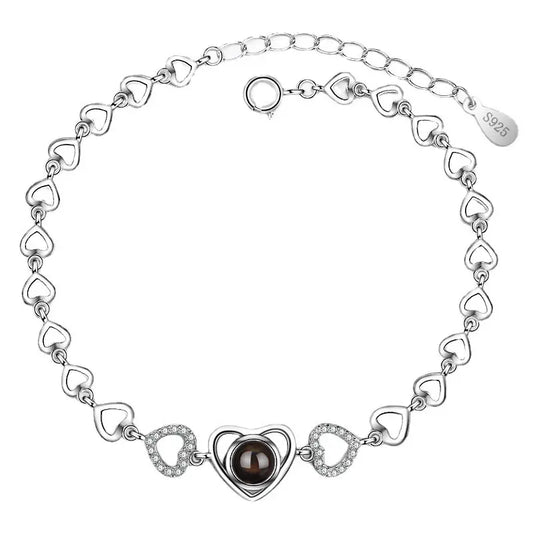 Silver heart-shaped necklace with a central black stone, adorned with smaller heart links and sparkling accents.